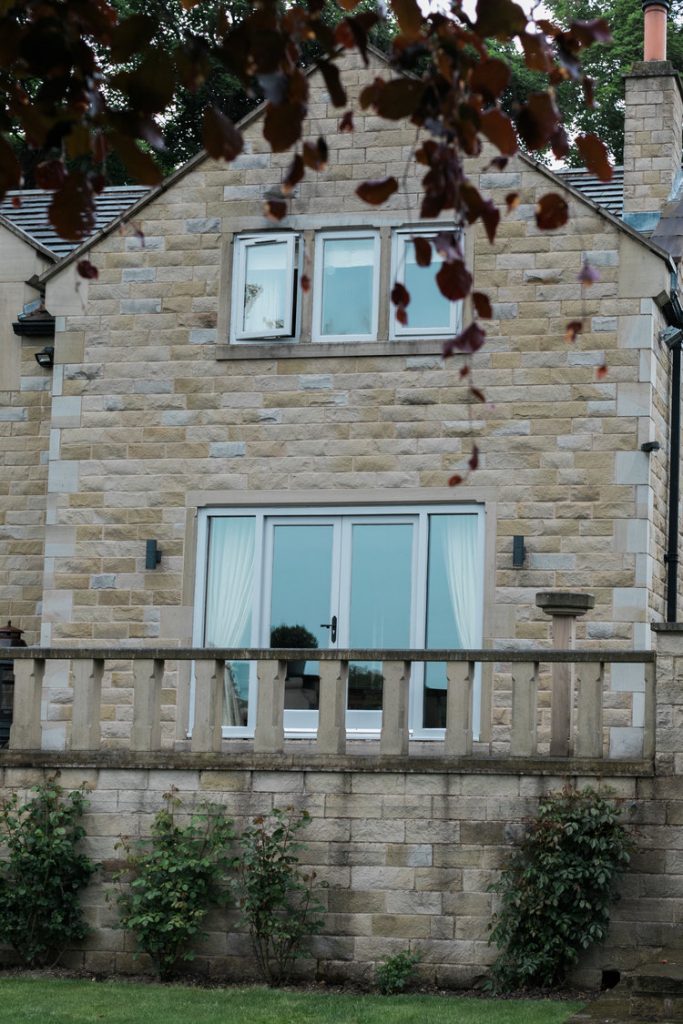 Close up of modern Yorkshire stone property fitted with light grey aluminium bi-folding doors supplied and installed by Valley Way Construction